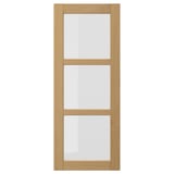 The FORSBACKA kitchen cabinet a warm oak finish with glass doors framed in bevelled edges, exuding a classic, traditional style.