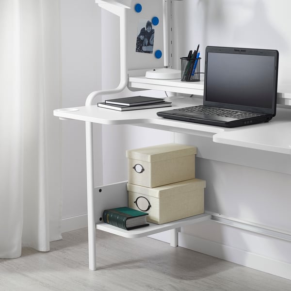 Modern white desk setup with laptop and storage, designed for comfortable work or gaming.
