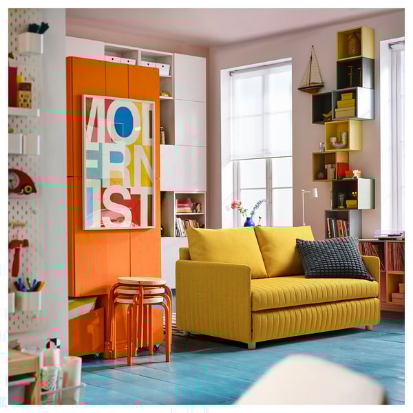 Bright living room with yellow FRIDHULT sofa, vibrant art, and multicoloured shelves.