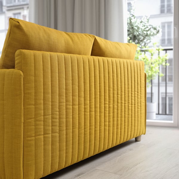 A modern yellow sofa bed by a large window, showcasing its minimalist design and vertical backrests.