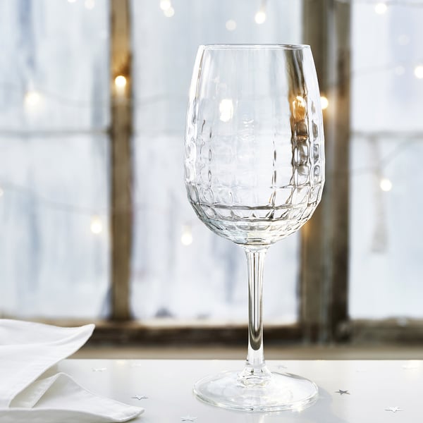 Elegant wine glass with faceted design stands on a pristine table setting, reflecting high quality and sophistication.