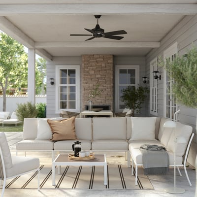 Modern outdoor patio with white furniture, ceiling fan, striped rug, and coffee table.