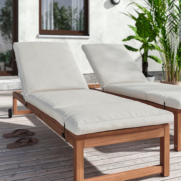 White FRÖSÖN/DUVHOLMEN lounge chairs on deck, large, cushioned, wooden, with flip flops nearby.