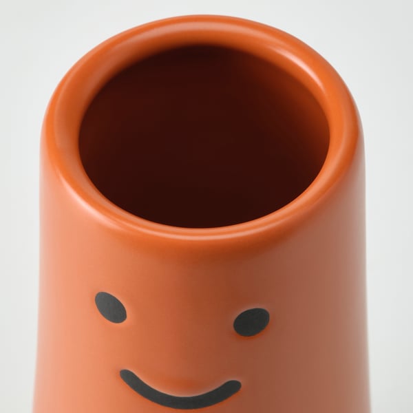 Cheerful orange vase with green eyes and smile.