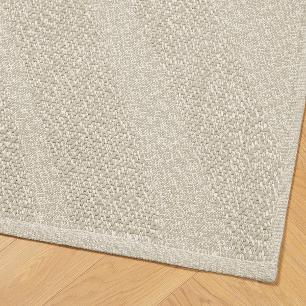 Light grey textured area rug on wood floor, thick weave, neatly bordered.