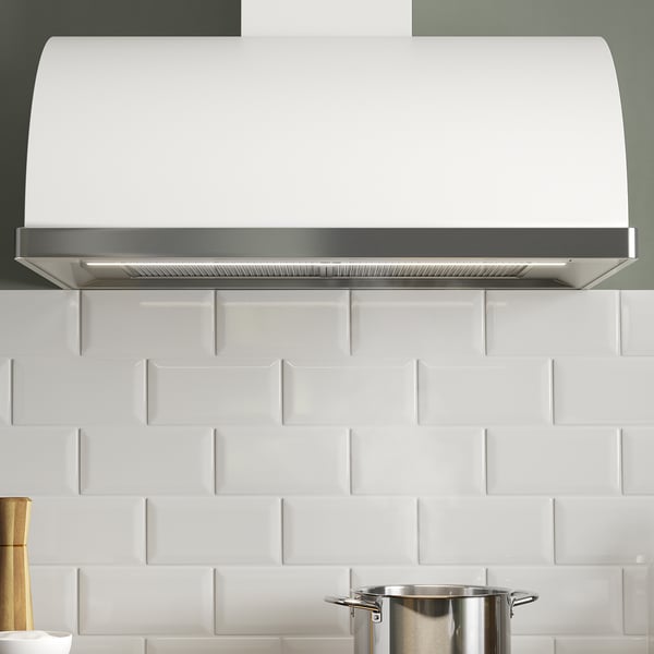 White kitchen hood mounted on tiled wall, featuring led lighting and multiple speed options.