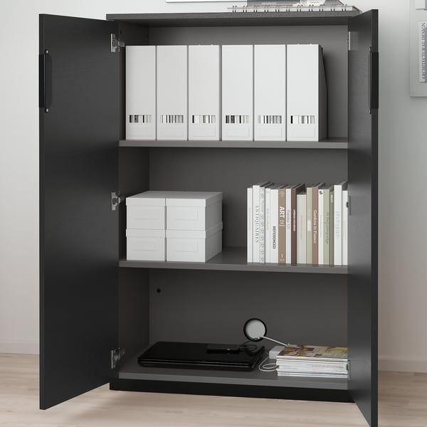 Open black office cabinet with adjustable shelves, storing white binders, folders, and books.