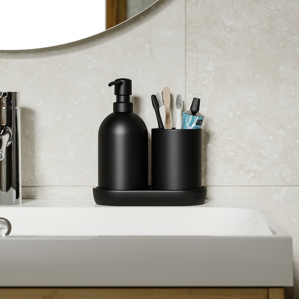 Black soap dispenser and toothbrush holder on white sink tray; stylish, functional bathroom essentials.