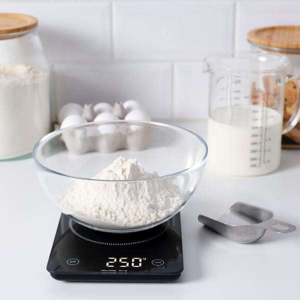 Glass bowl with flour on digital kitchen scale, measuring ingredients precisely.