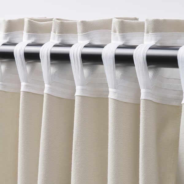Close-up of beige curtains with rod pocket and pleats.