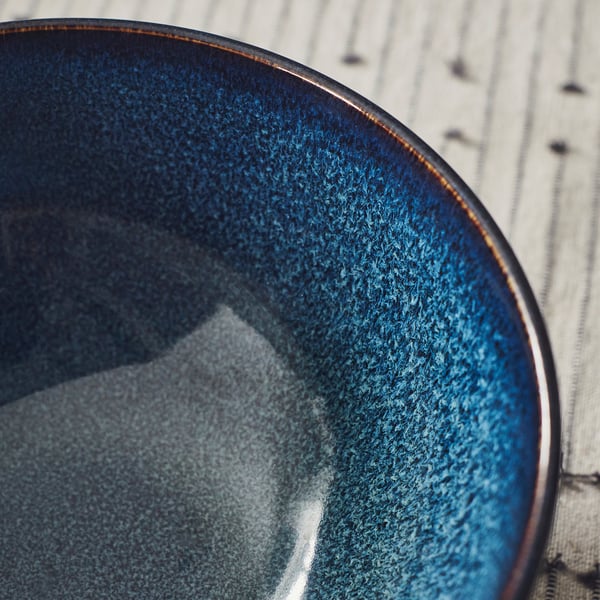 Blue bowl with golden rim on light wood.