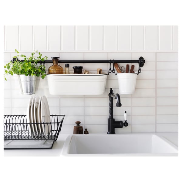 Modern kitchen sink with black GLITTRAN faucet, white accessories, and green plant.