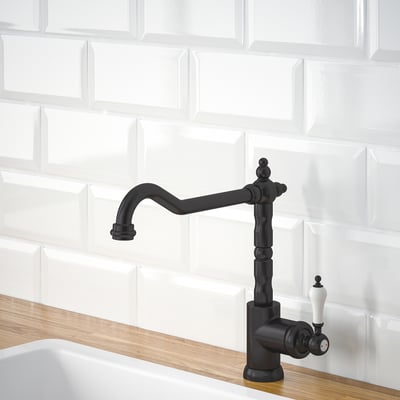 Black kitchen tap with curved spout and white handles on wooden countertop.