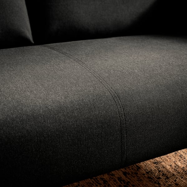 Black fabric sofa close-up, showing smooth texture, neat stitching, and sturdy wooden base.