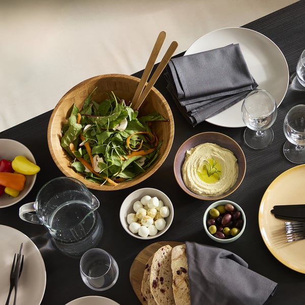 Wooden bowl with salad, table setting.