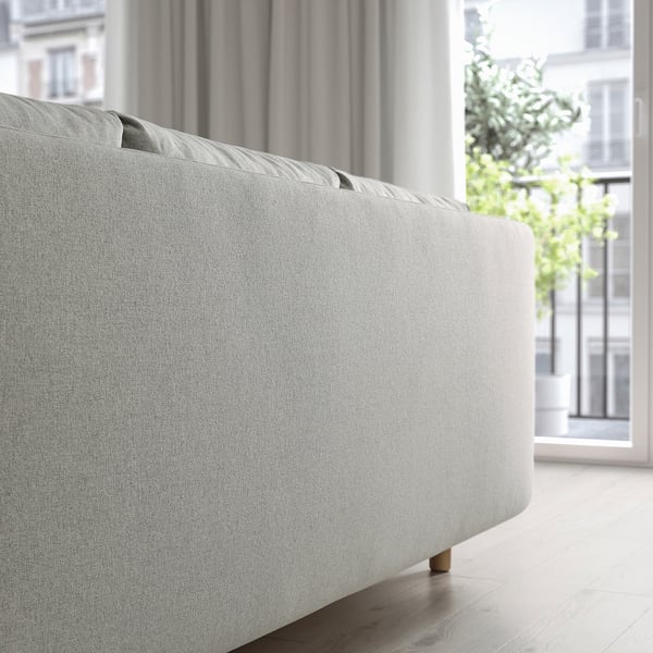 GRUNNARP sofa-bed, converts to bed. Plush cushions, storage, wide legs. Bright window with plants.