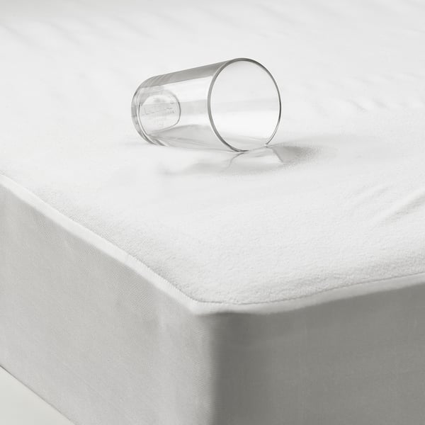 Plastic glass tilted on waterproof mattress protector with elastic edges.