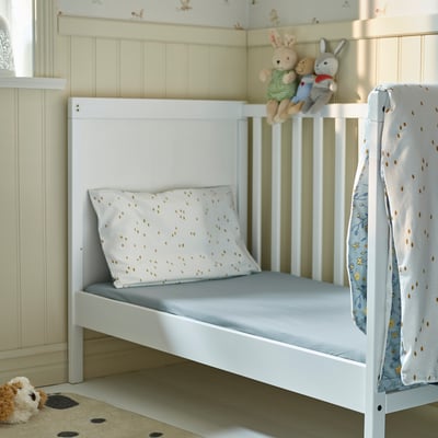Toddler bed with light blue sheet, nursery with toys.