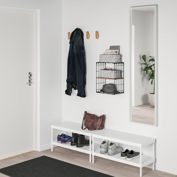 White wall shelf with hooks, mirror, and jacket.