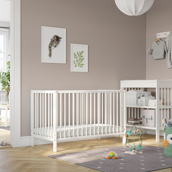 GULLIVER white cot in a nursery; larger than the nearby play mat and toys.