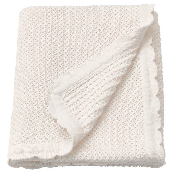 Folded white cotton baby blanket; soft, knitted with fringe edges.