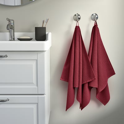 Two burgundy GULVIAL towels hang on wall hooks beside a white sink.