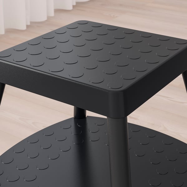 Black step stool with textured non-slip surface, sturdy metal legs, and a shelf, designed for stability and safety.