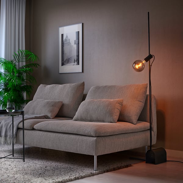 Modern living room with grey HÅRSLINGA floor lamp, soft lighting, and cushioned chair.