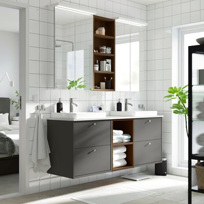 Modern black bathroom vanity with dual sinks, open shelves, and sleek cabinetry. Large mirror above with towels and plant.