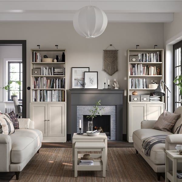 Cosy living room with HAVSTA light grey bookshelves and white sofas, featuring a fireplace, pendant light, and various decorations.