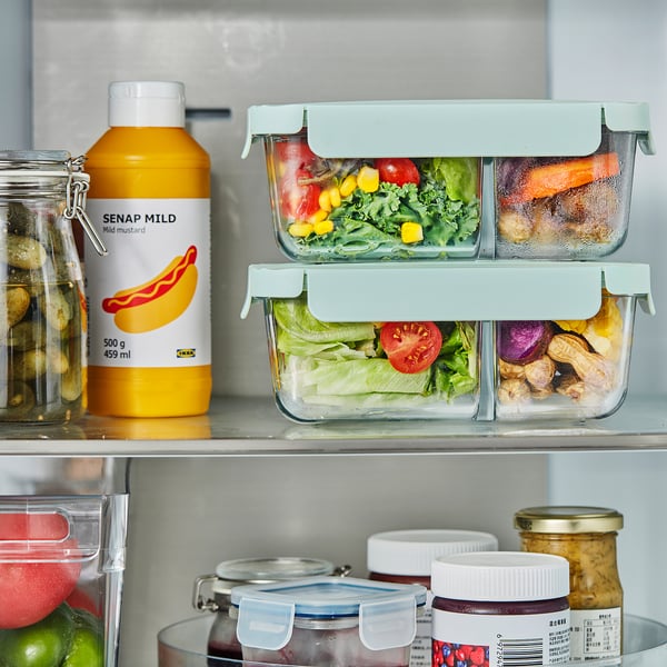 Fridge shelf with glass HAVSTOBIS lunch boxes, storing vegetables separately in compartments. Next to yellow mustard bottle labelled senap mild.