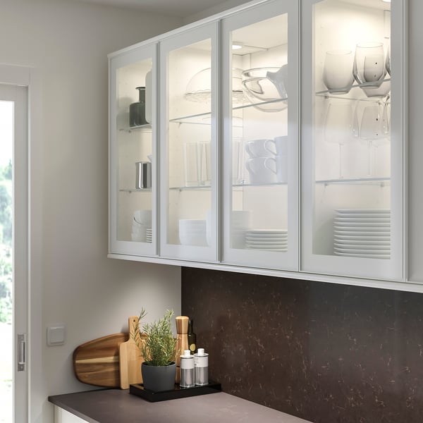 Kitchen with white HEJSTA cabinets. Plates, bowls, wine glasses, plant, cutting board, oils.