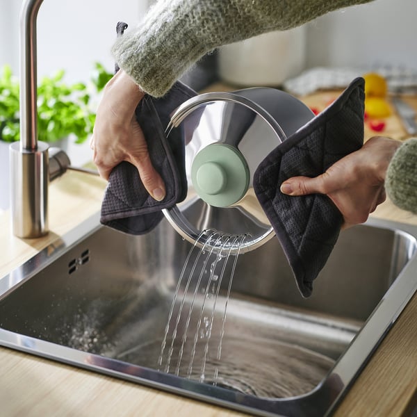 Person washes pots under tap, demonstrating easy handling and thorough cleaning process.
