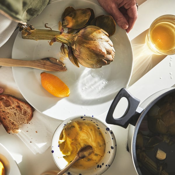 Artichoke, bread, sauce on table.