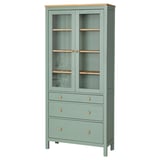 A green HEMNES glass-door cabinet with wooden accents, featuring drawers and adjustable shelves.