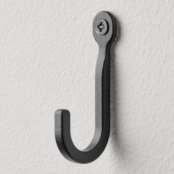 Single black metal hook on white wall, robust and minimalist design.
