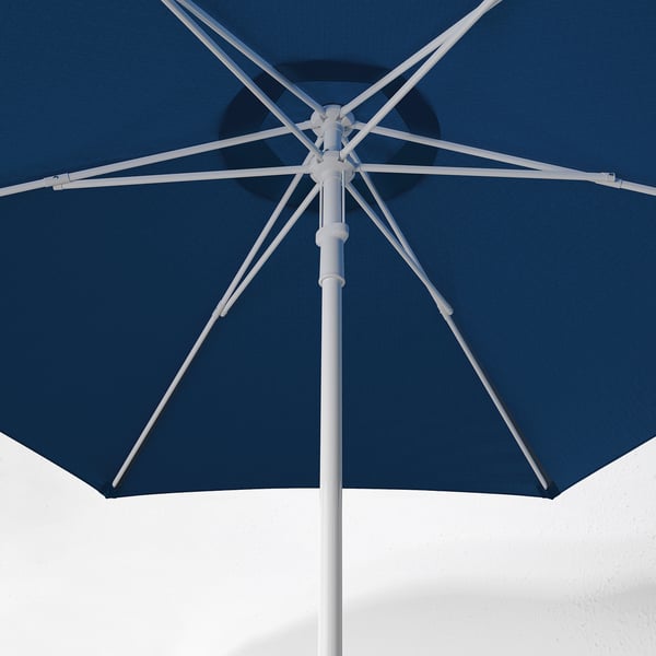 Blue patio umbrella with white frame, partially open against white wall. Shows sturdy design and air vent for wind pressure reduction.