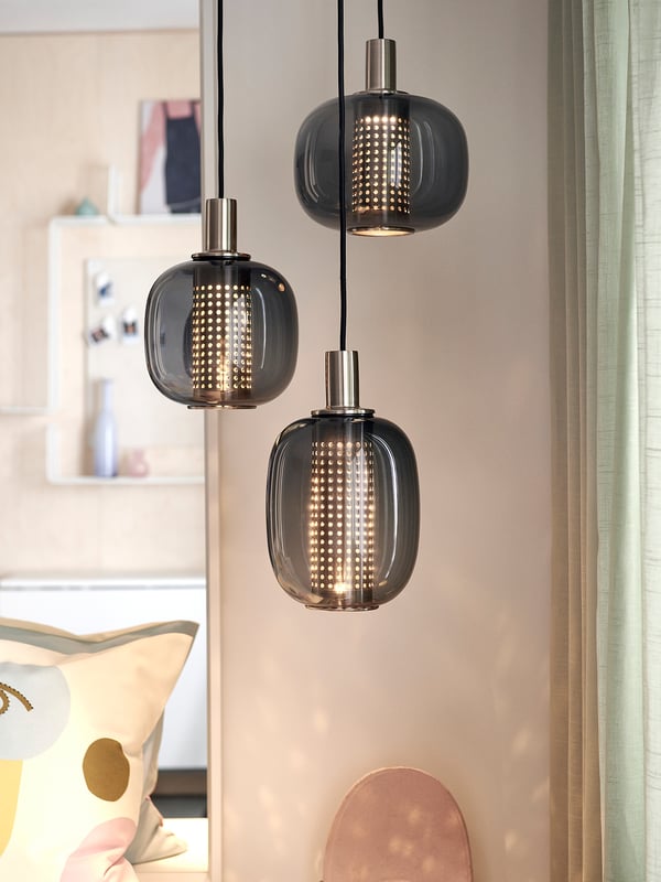 Three smoky glass pendant lamps with perforated shades, brass finish.
