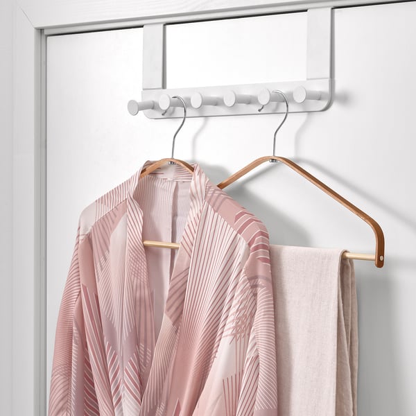 A light pink patterned robe hangs on a bamboo hanger, suspended from a white over-door hook rack.