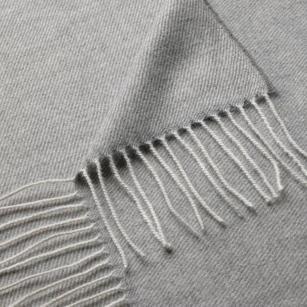 Soft, grey throw blanket with intricate, evenly spaced fringes along the edge.