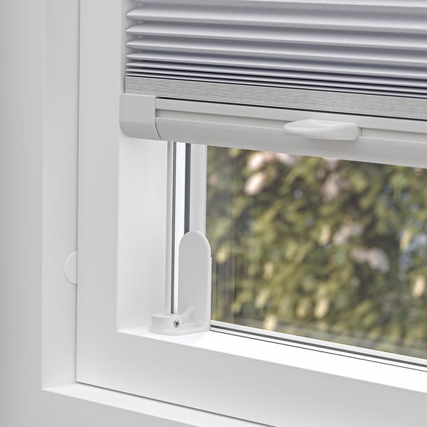Window blind partially open, showing cordless design for safety. Top handle visible, enabling control of light blockage.