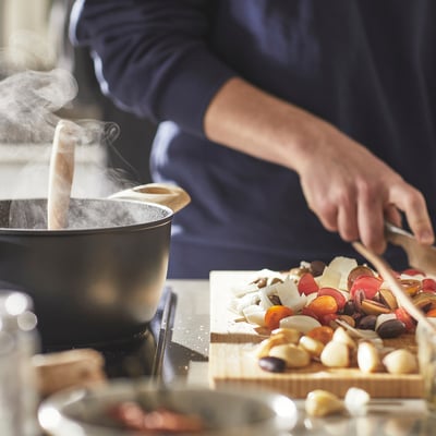 Chef cooks, chops veggies, steam vent open, non-stick pan.