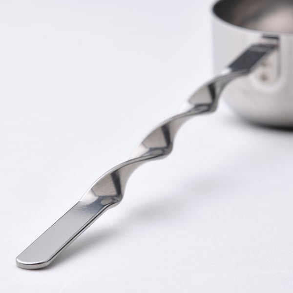 Stainless steel scoop with wavy handle rests on white surface, showcasing its sturdy and sleek design.