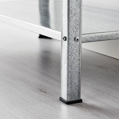 Image shows a close-up of a sturdy, galvanised metal shelf leg on a wooden floor. The leg adjustable black plastic feet for floor protection.