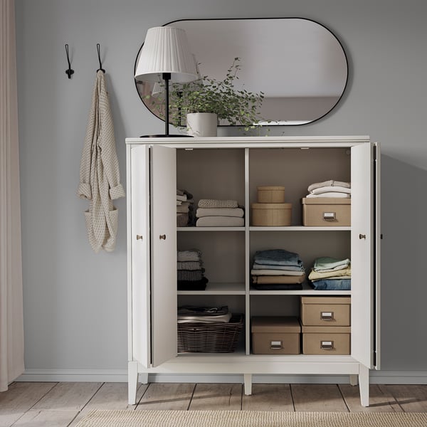 Organised storage cabinet IDANÄS with folded doors, white, holding clothes, boxes, and books. Stylish and functional.