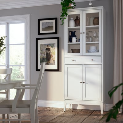 White IDANÄS cabinet with glass doors, solid wood, sleek design. Top glass, bottom solid. Displays items.