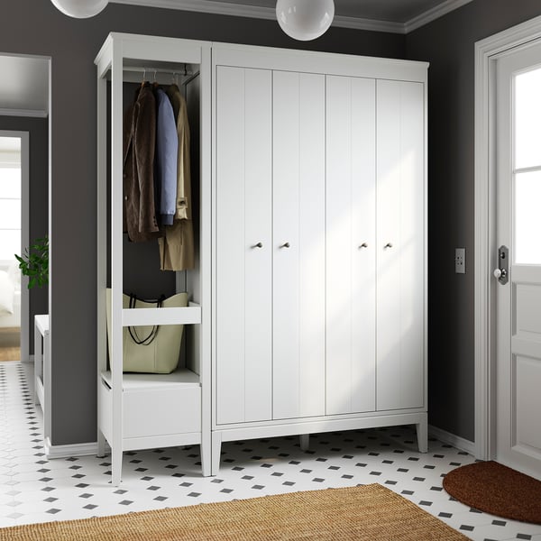 IDANÄS wardrobe with bifold doors, shelves, and hanging space against dark wall, natural light.