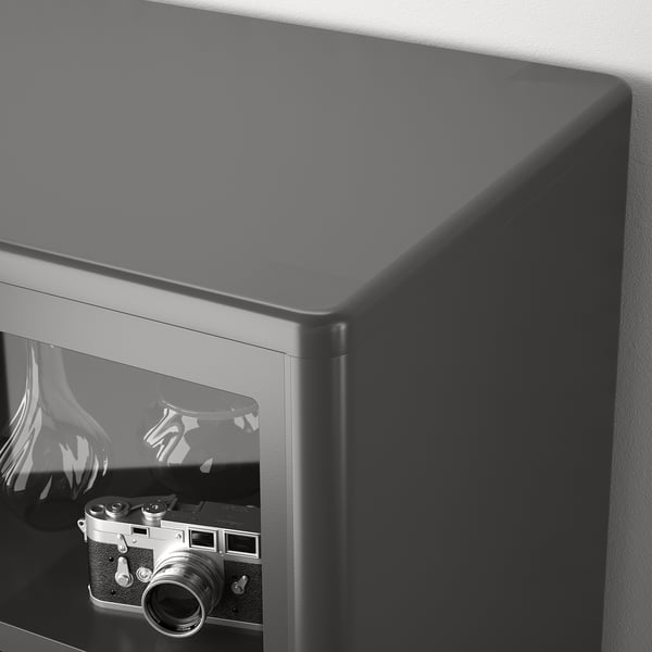 Black glass cabinet with sliding doors, showcasing vintage camera inside.