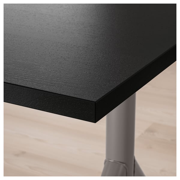 Black desk corner with thick, smooth tabletop supported by a sturdy metal leg.