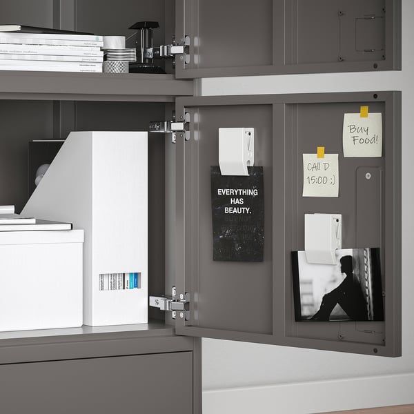 Modern grey office cabinet with open door exposing internal organisation: file folders, memo board with notes, and photo.